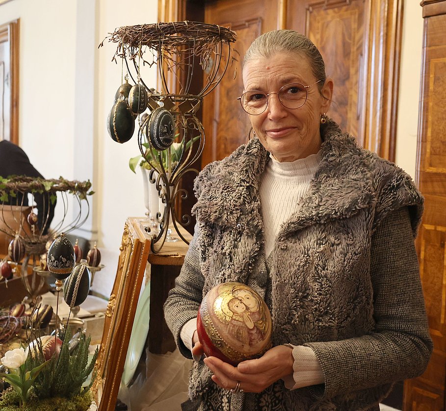 Eine Frau hält ein bemaltes Straußenei in die Kamera.