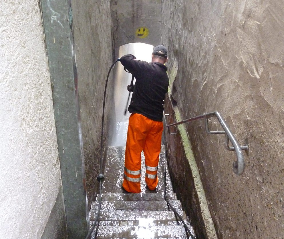 Ein Bauhofmitarbeiter beim Reinigen einer Treppe von Taubendreck.