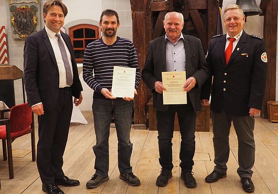 Vier Männer, zwei mit Urkunden