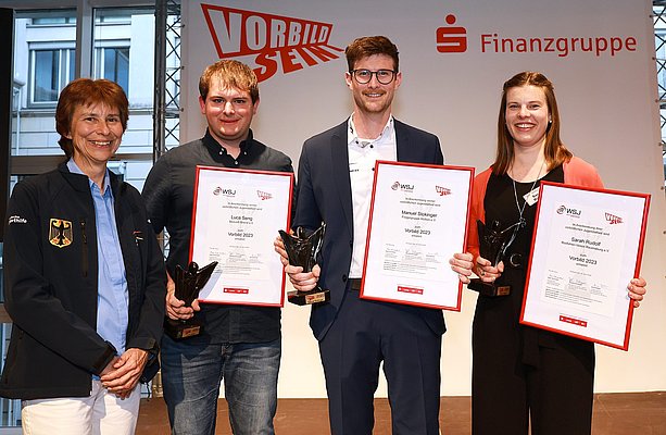 Zwei Frauen und zwei Männer, eine Frau hat Urkunden an die anderen überreicht