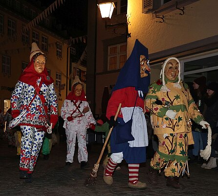 Verschiedene Narren der Narrenzunft Kuhschelle weiß-rot und eine Mühlhexe