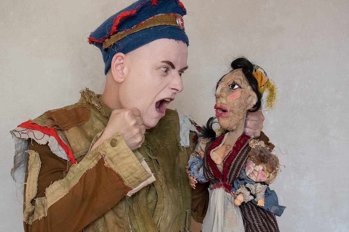 Ein Mensch mit einer Art Kasper-Figur. Beide sind verkleidet.