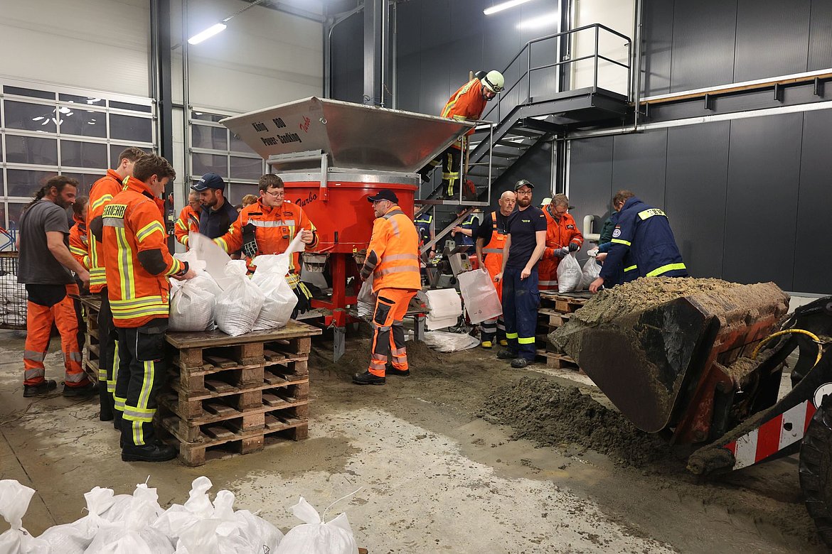 Im Bauhof füllen Menschen Sandsäcke