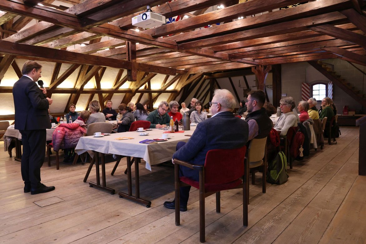 Oberbürgermeister Michael Lang spricht vor Menschen im Sitzungssaal des Rathauses.