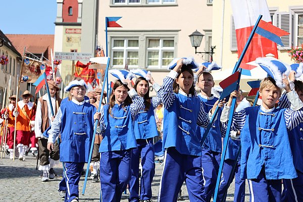 Schülerinnen und Schüler in blauen Uniformen mit Dreispitz auf dem Kopf