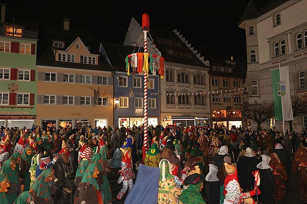 Viele Narren verschiedener Zünfte tanzen um den Narrenbaum
