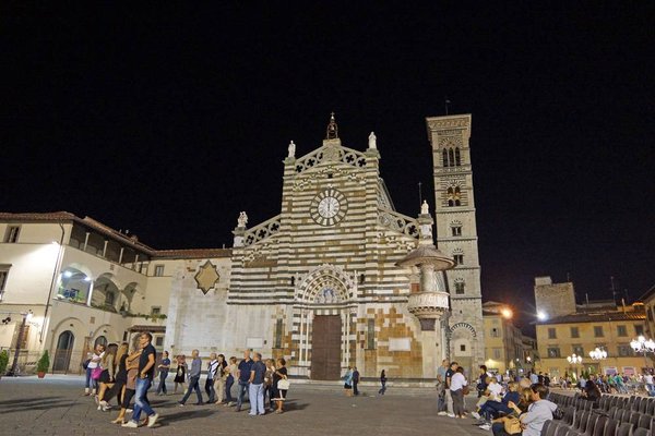 Nächtliche beleuchtete und belebte Straßenszene in Prato, im Hintergrund der dom