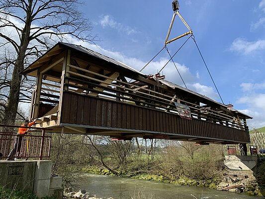 Handwerker setzen vorsichtig die Holzbrücke bei Jussenweiler ein.