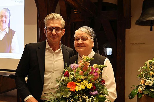 Roy Hummel, der Geschäftsführer der Vinzenz von Paul gGmbH überreicht Schwester Bonavita einen Blumenstrauß.