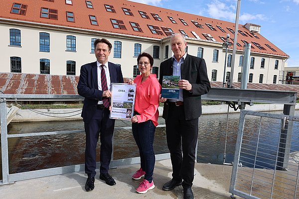 OB Michael Lang, Susanne Müller, Rainer Jensch mit Plakaten vor der Alten Spinnerei