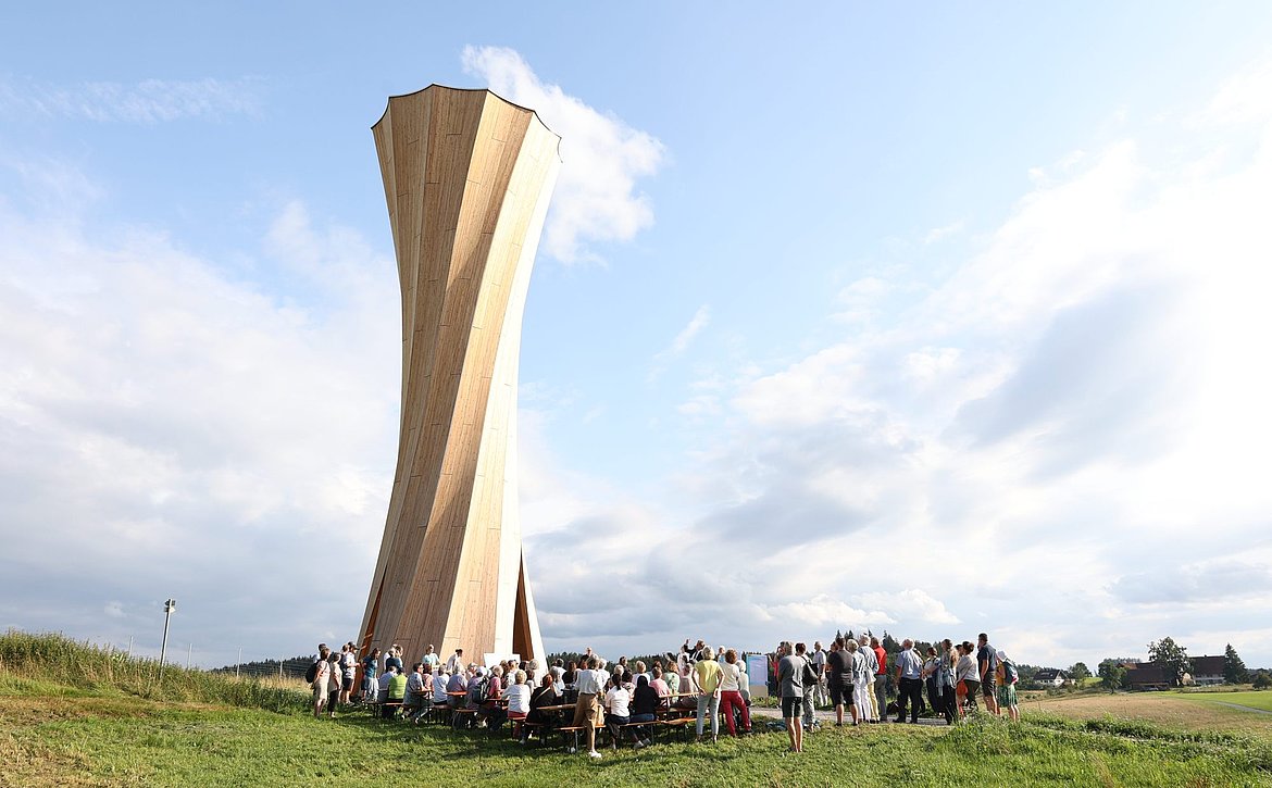 Aussichtsturm mit vielen Menschen auf Bierbänken
