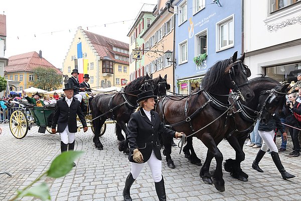 Ein Fünfergespann mit Menschen in Kleidung aus dem 19. Jahrhundert.
