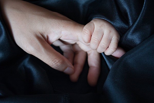 Babyhand umgreift erwachsenen Finger