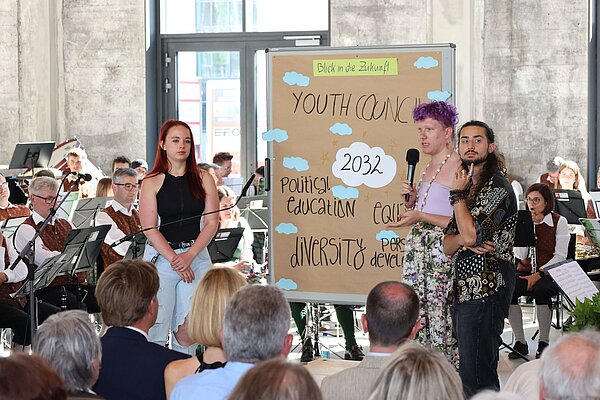 Junge Menschen zeigen auf einer Präsentationswand, wie sie sich ihre Stadt wünschen