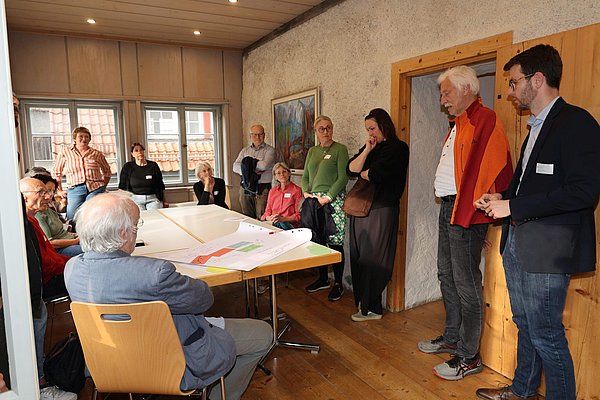 Menschen diskutieren in einem kleinen Raum an einem Tisch