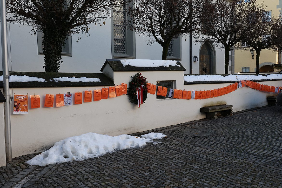 Viele Orangefarbene Blätter hängen wie an einer Wäscheleine an der Mauer am Marktplatz
