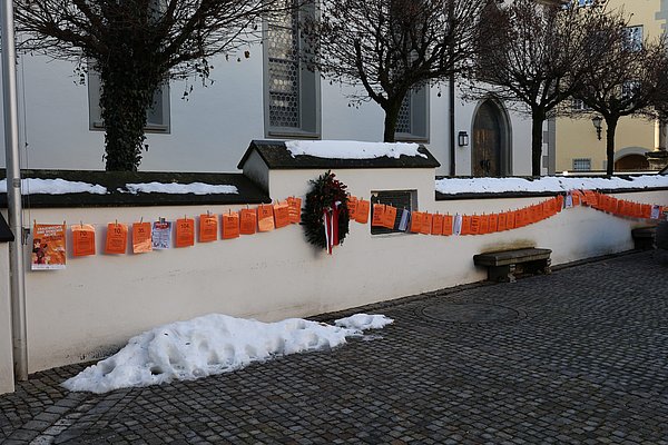 Viele Orangefarbene Blätter hängen wie an einer Wäscheleine an der Mauer am Marktplatz