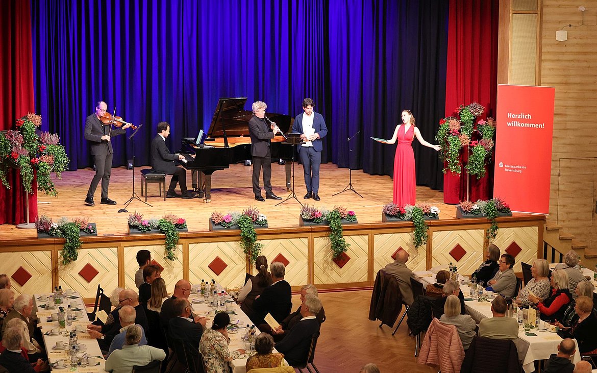Drei Musiker und eine Sängerin und ein Sänger auf einer Bühne
