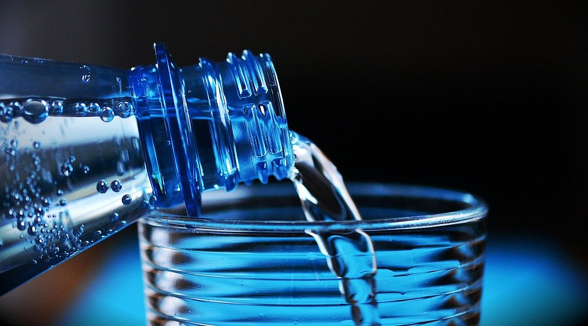 Symbolbild: aus einer Flasche fließt Wasser in ein Glas
