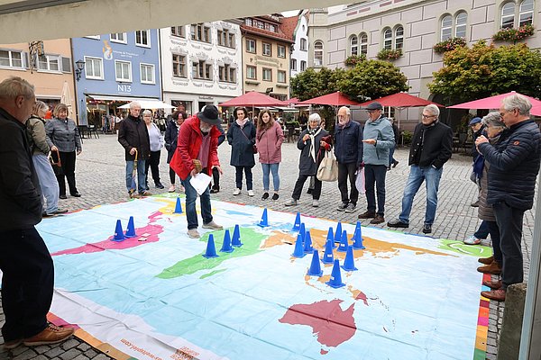 Menschen stehen um eine große Landkarte, die auf dem Fußboden liegt.