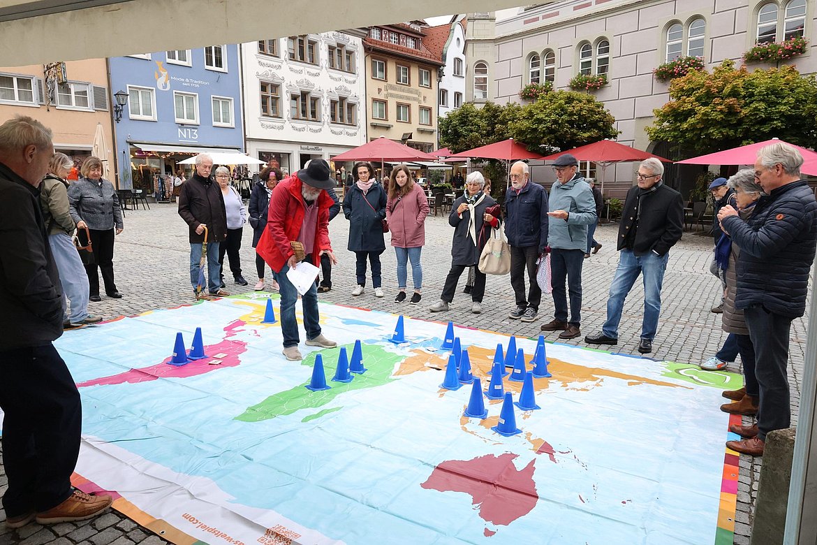 Menschen stehen um eine große Landkarte, die auf dem Fußboden liegt.