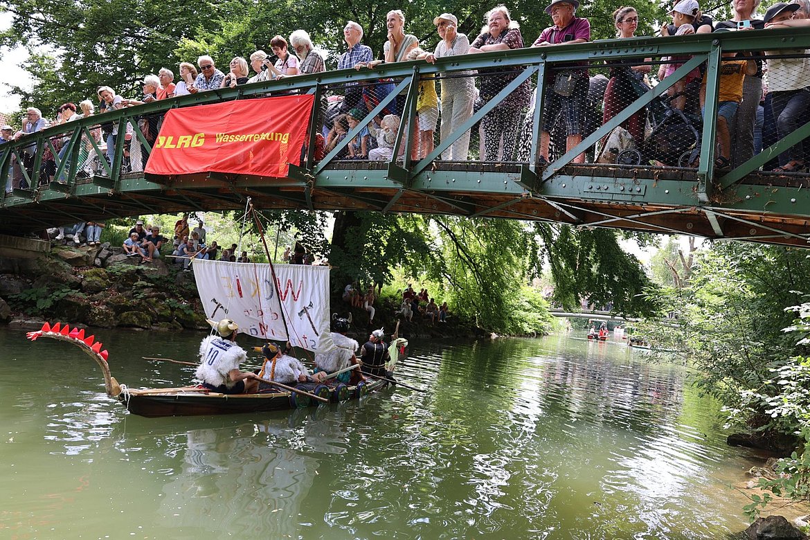 Viele Menschen stehen auf einem Steg. Ein Boot fährt unten durch.