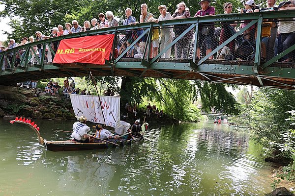 Viele Menschen stehen auf einem Steg. Ein Boot fährt unten durch.