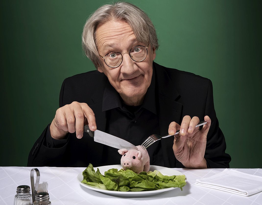 Ein Mann mit einem Plüsch-Schweinchen auf dem Teller.