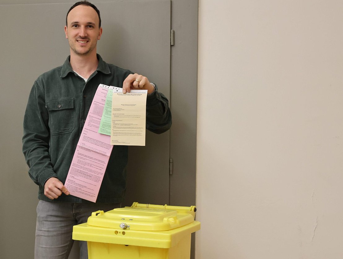 Ein Mann zeigt die Wahlzettel für die Kommunalwahlen.