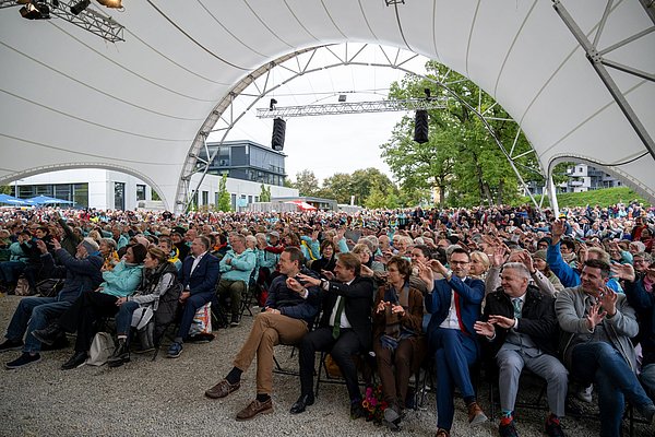 Tausende Menschen mit den Händen über dem Kopf und lachend