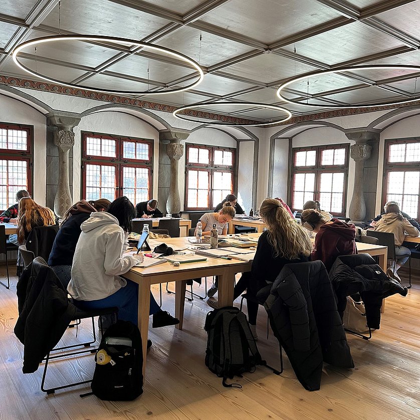 Junge Leute beim Lernen an Tischen im Lesesaal der Stadtbücherei.