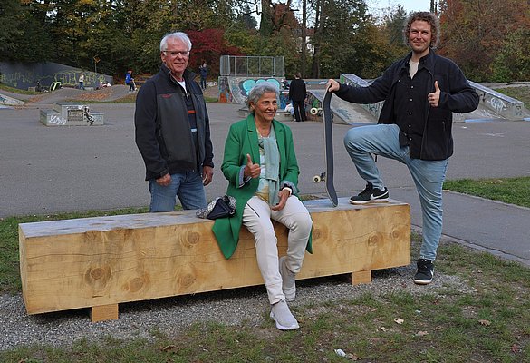 Eine Sitzgelegenheit aus Holz und drei Personen