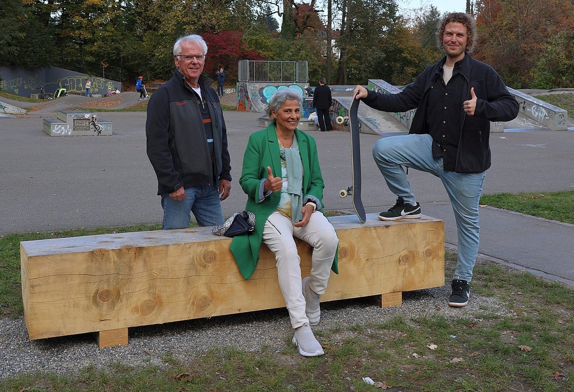 Eine Sitzgelegenheit aus Holz und drei Personen