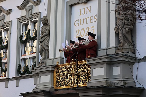 Drei Männer spielen Trompete auf dem Balkon des Marktplatzes