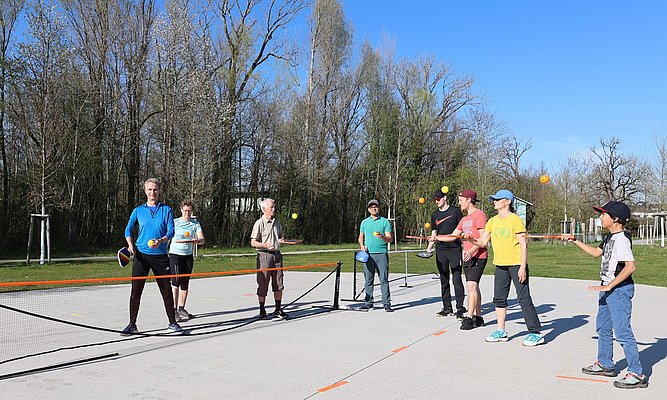 Eine Gruppe Menschen auf einem Sportplatz, die mit Schlägern Bälle in die Luft spielt