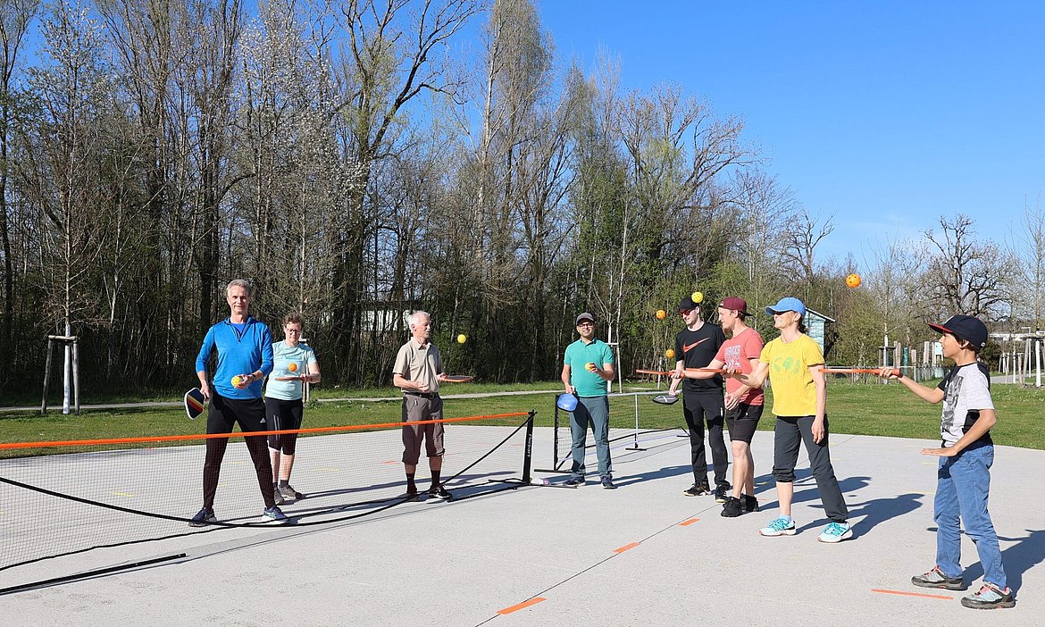 Eine Gruppe Menschen auf einem Sportplatz, die mit Schlägern Bälle in die Luft spielt