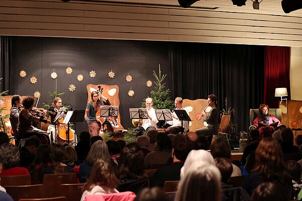 Musikerinnen und Musiker auf Weihnachtlich dekorierter Bühne