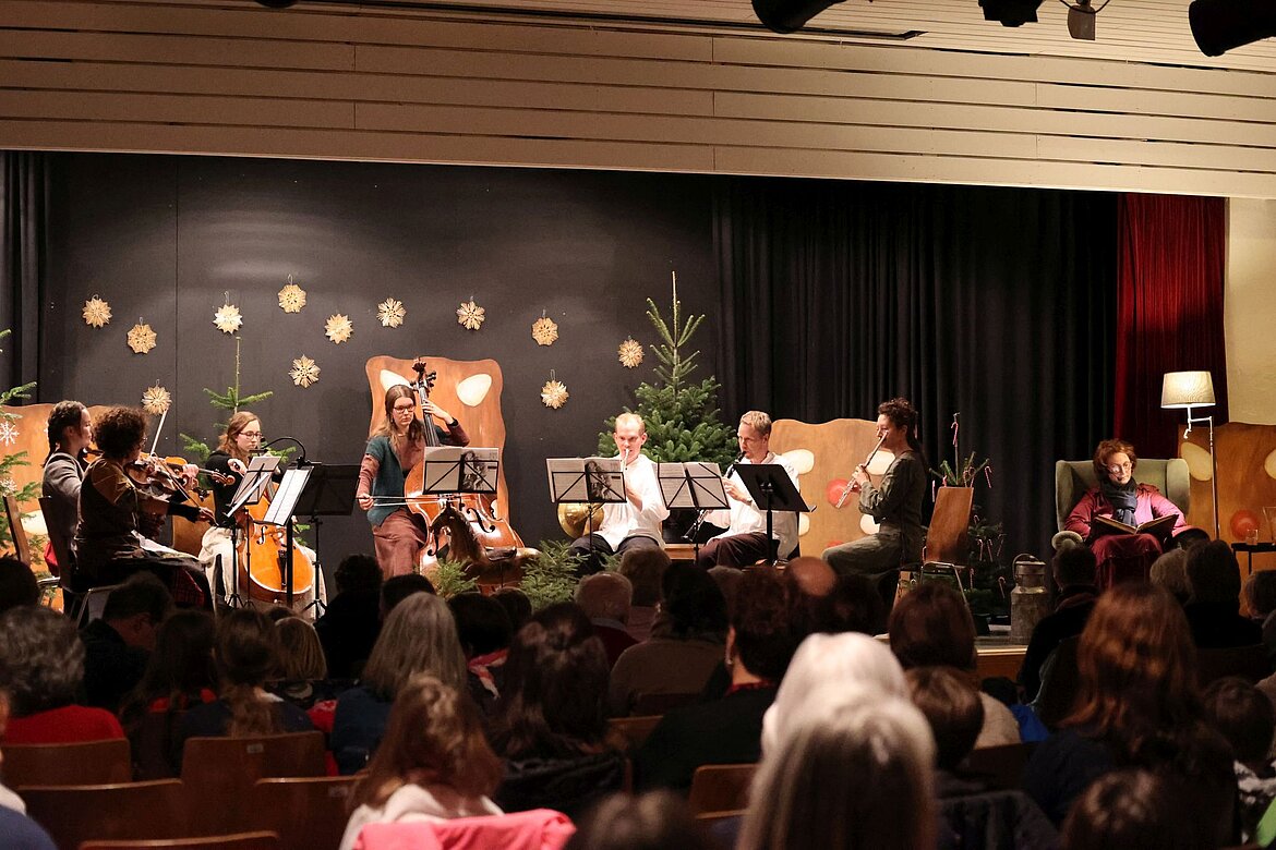 Musikerinnen und Musiker auf Weihnachtlich dekorierter Bühne