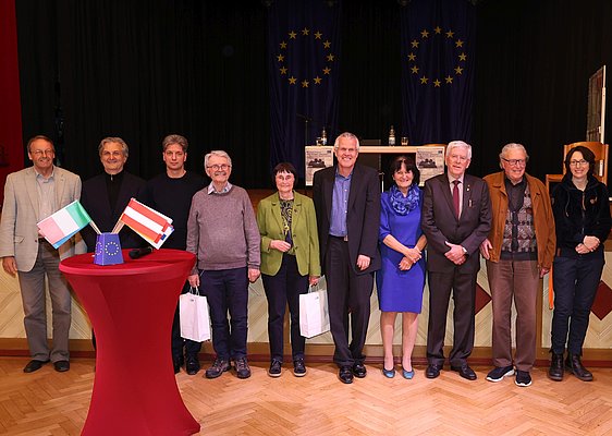 Eine Gruppe vor der Bühne in der Stadthalle, im Hintergrund zwei Europaflaggen