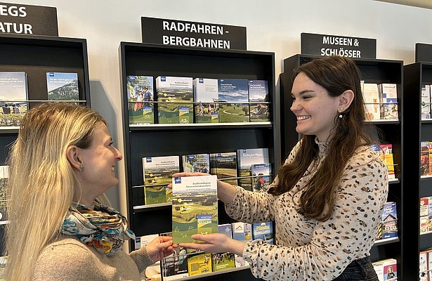 Eine Frau überreicht einer anderen eine Broschüre