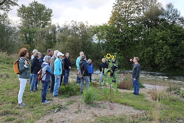 Gruppe Menschen an der Argen, die einem Mann zuhört
