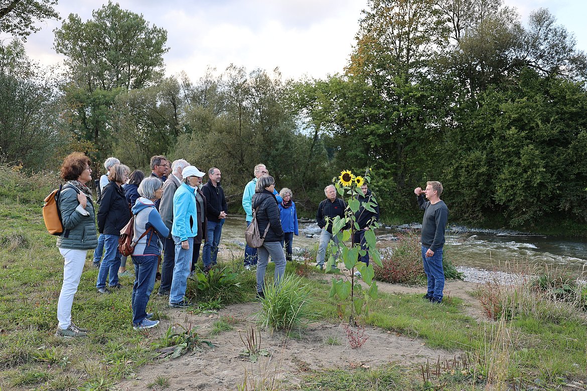 Gruppe Menschen an der Argen, die einem Mann zuhört