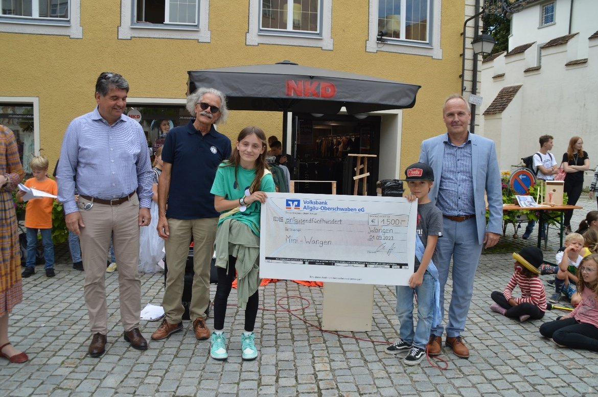 Drei Männer und zwei Kinder mit einem symbolischen Scheck über 1500 Euro