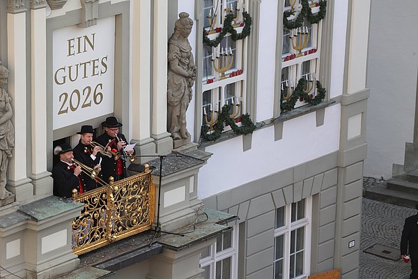 Drei Fanfarenbläser auf dem Rathausbalkon.