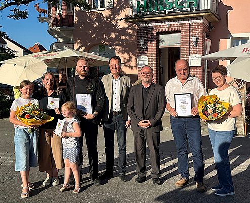 Die Preisträger und die Auszeichenenden stehen nebeneinander mit Urkunden und Blumensträußen