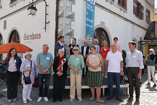Mehrere Personen auf eine Bühne und andere davor.