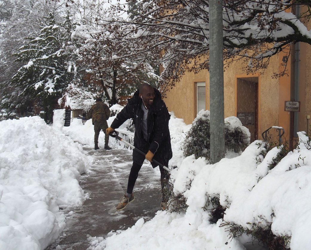 Mann, der mit der Schneeschaufel den Gehweg räumt
