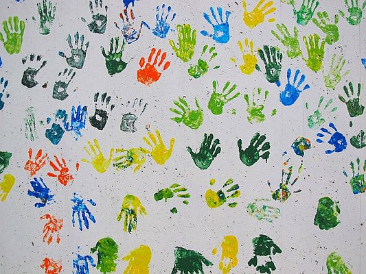 Handabdrücke von Kindern in bunter Farbe auf weißem Untergrund