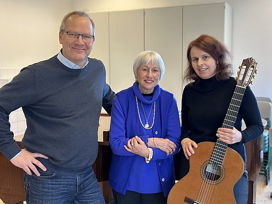 Ein Mann und zwei Frauen, eine mit einer Gitarre in der Hand.