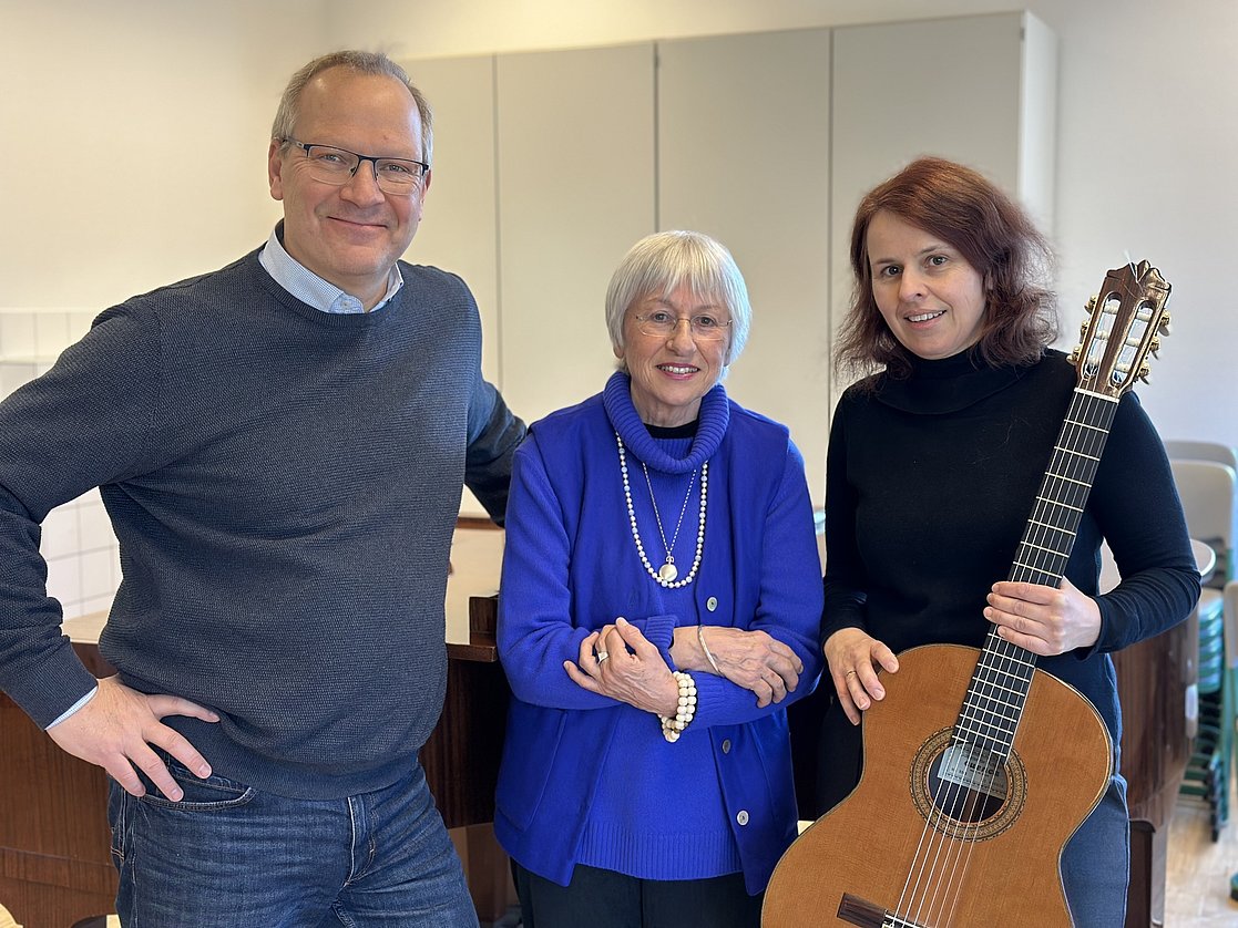 Ein Mann und zwei Frauen, eine mit einer Gitarre in der Hand.